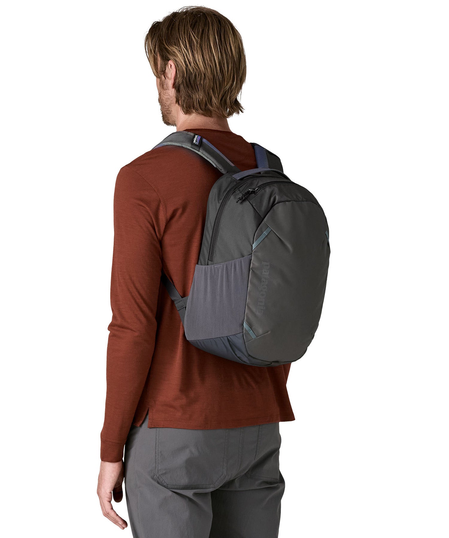 A reverse image of a man wearing the Patagonia smolder  blue 24L atom day pack available at Babipur.