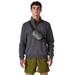 A man wearing the Patagonia terravia mini bum bag in noble grey over the shoulder available at Babipur