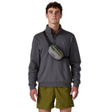 A man wearing the Patagonia terravia mini bum bag in noble grey over the shoulder available at Babipur