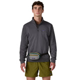 A man wearing the Patagonia terravia mini bum bag in noble grey available at Babipur around the waist showing the zipped compartment on the front panel