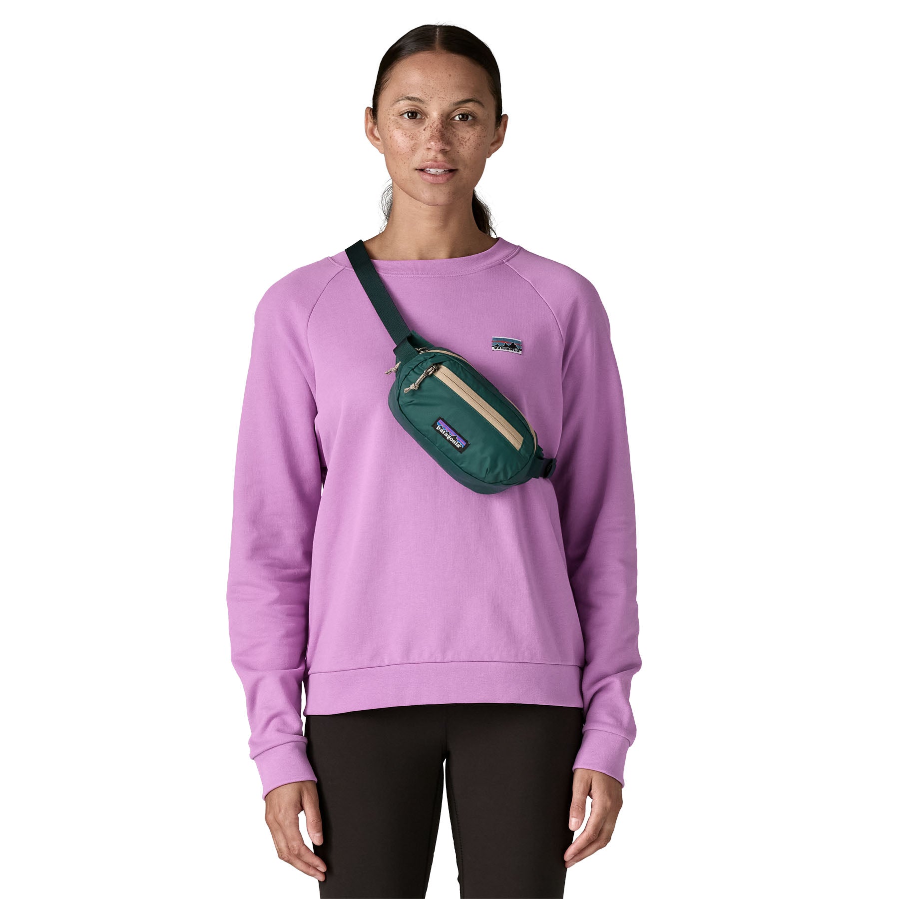A woman wearing the Patagonia terravia mini bum bag in cascade green over the shoulder available at Babipur