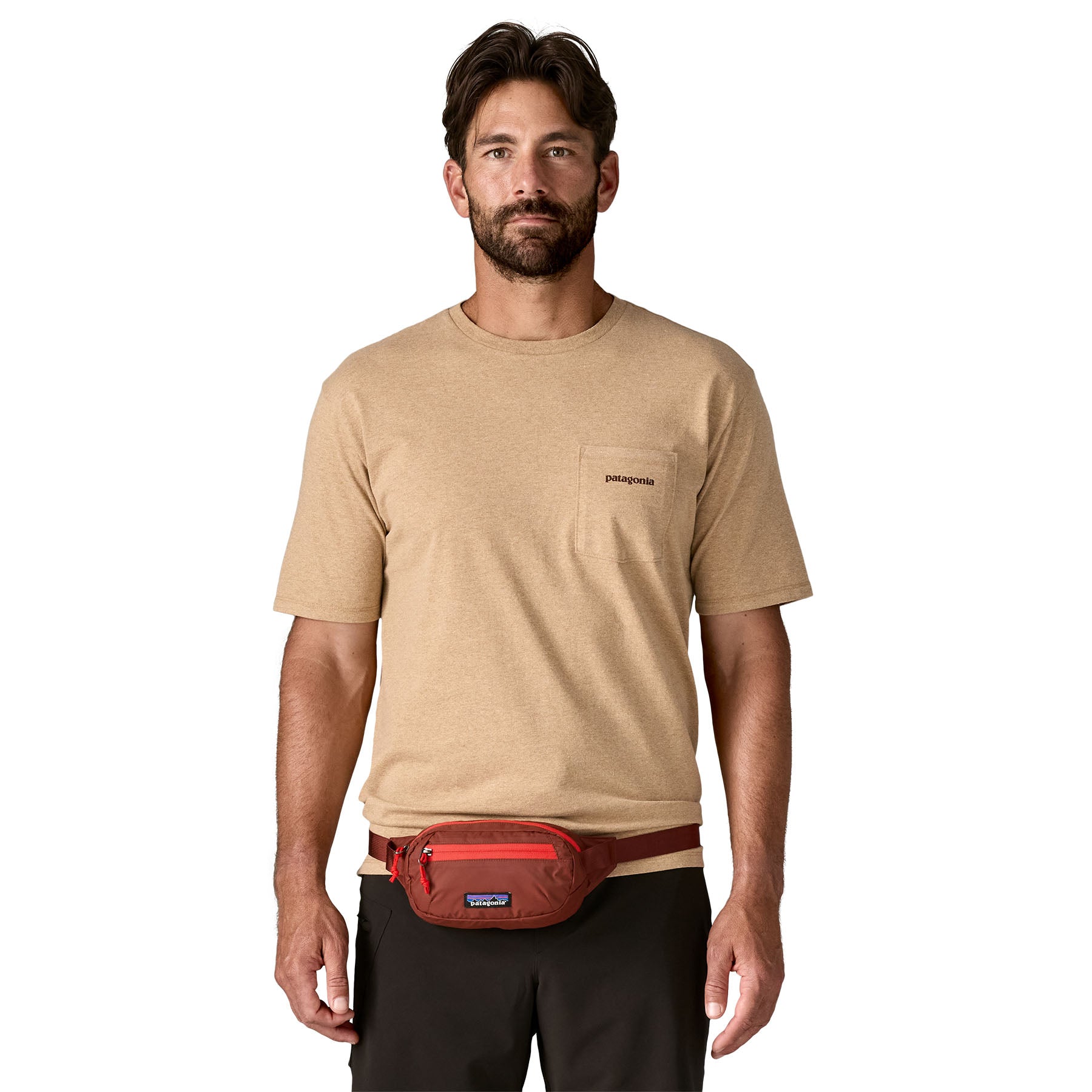 A man wearing the Patagonia terravia mini bum bag in dried vanilla available at Babipur around the waist showing the zipped compartment on the front panel