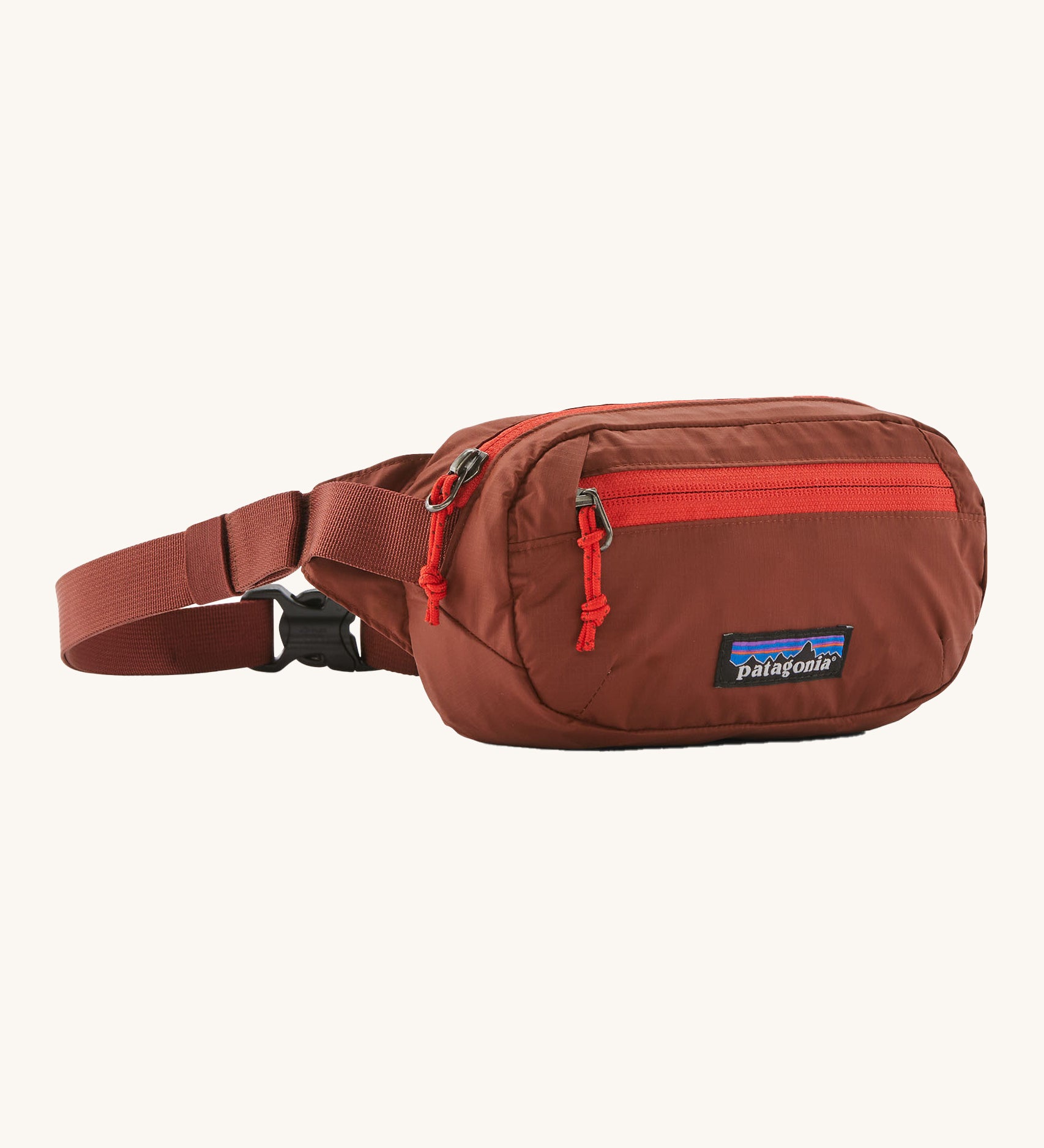 Patagonia terravia mini bum bag in dried vanilla available at Babipur. A 100%  recycled material pack in dark red with bright red detail. Features 2 main zipped compartments and a buckle fastener 