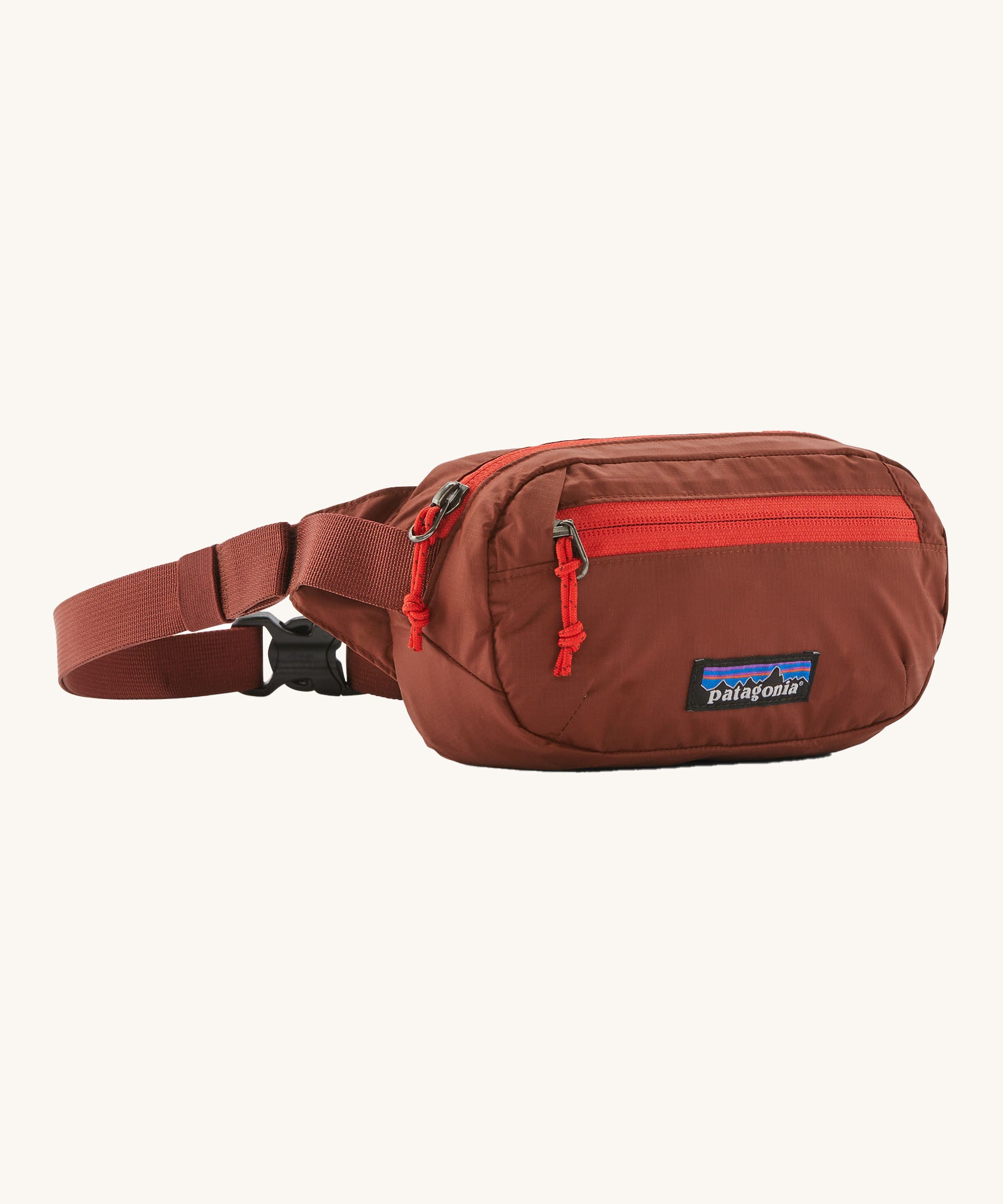 Patagonia terravia mini bum bag in dried vanilla available at Babipur. A 100%  recycled material pack in dark red with bright red detail. Features 2 main zipped compartments and a buckle fastener 