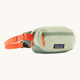 Patagonia terravia mini bum bag in lichen green available at Babipur. A 100%  recycled material pack in pastel green with bright orange detail. Features 2 main zipped compartments and a buckle fastener on a orange strap