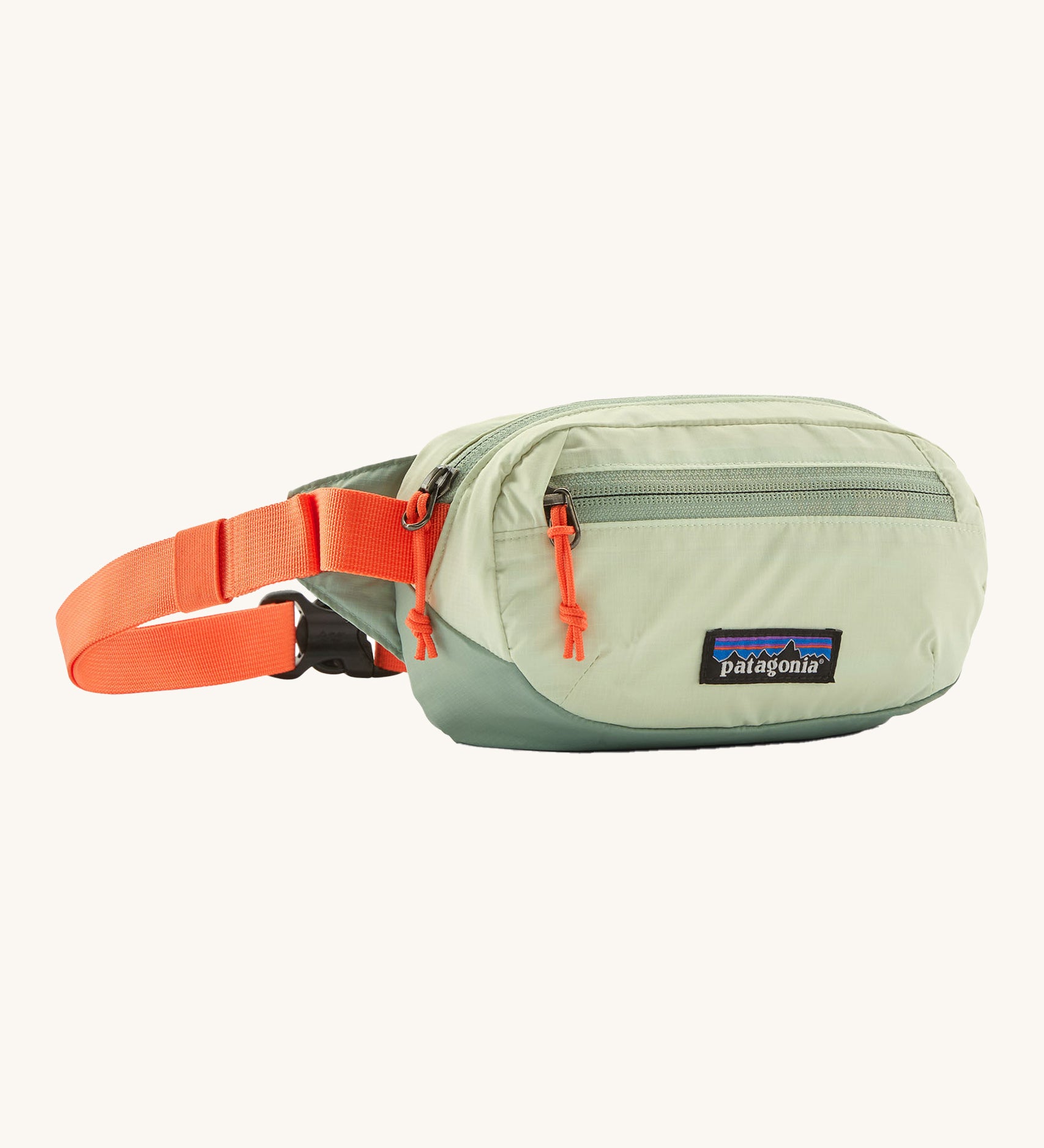 Patagonia terravia mini bum bag in lichen green available at Babipur. A 100%  recycled material pack in pastel green with bright orange detail. Features 2 main zipped compartments and a buckle fastener on a orange strap