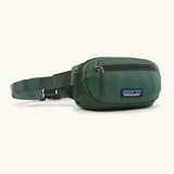 Patagonia 100% recycled nylon weather resistant terravia mini hip pack in dark green. Features 2 compartments with zipper fasteners