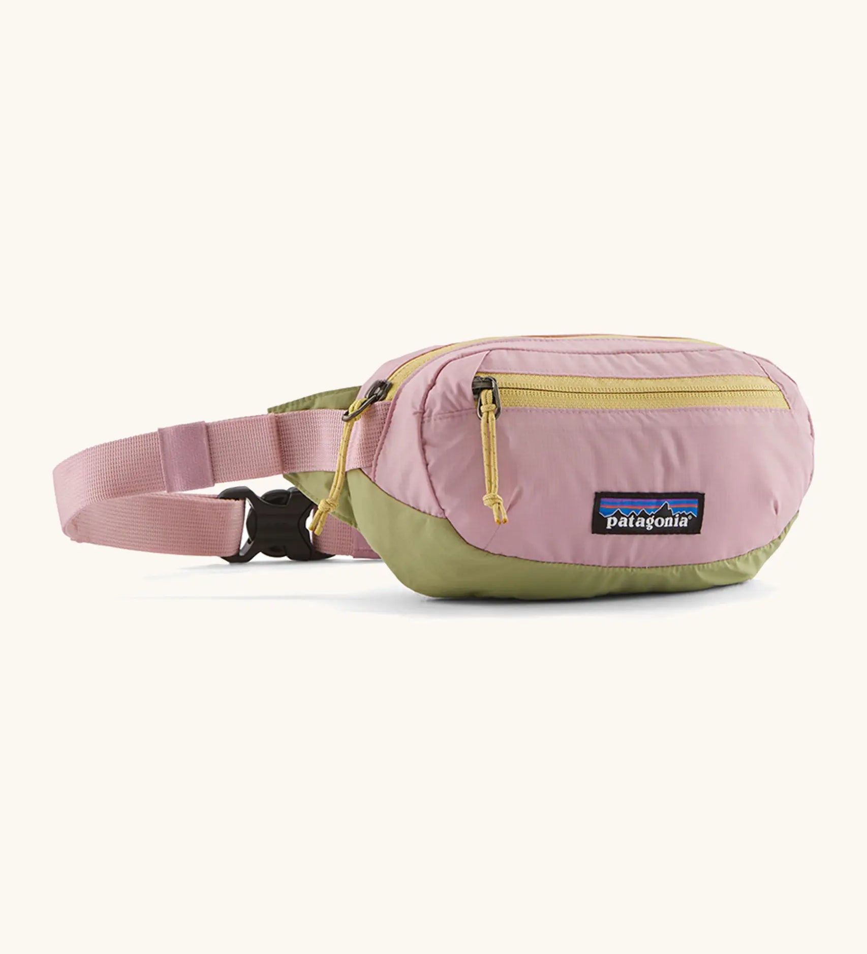 Patagonia recycled nylon terravia mini hip pack in pale pink with green bottom panel. Shows 2 zipped front pockets