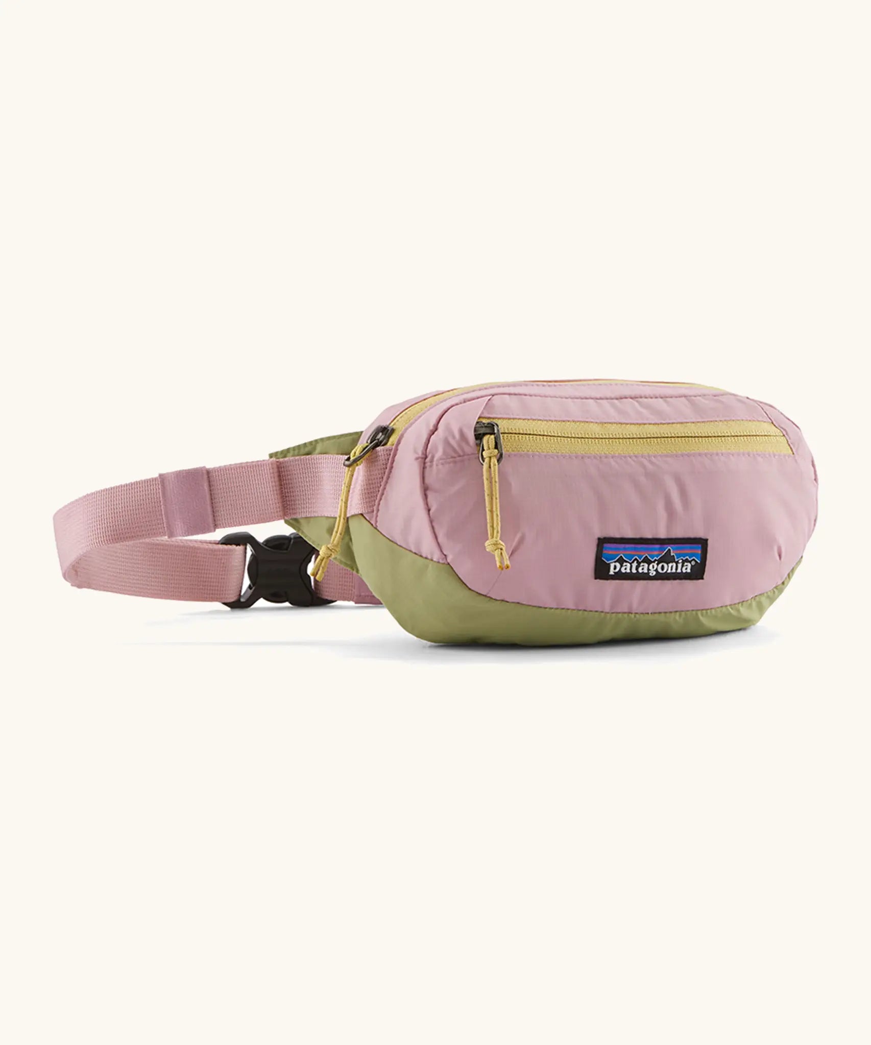 Patagonia recycled nylon terravia mini hip pack in pale pink with green bottom panel. Shows 2 zipped front pockets