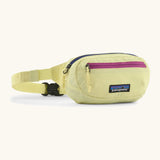 Patagonia 100% recycled nylon weather resistant terravia mini hip pack in pale yellow. Features 2 compartments with navy and pink zip detail