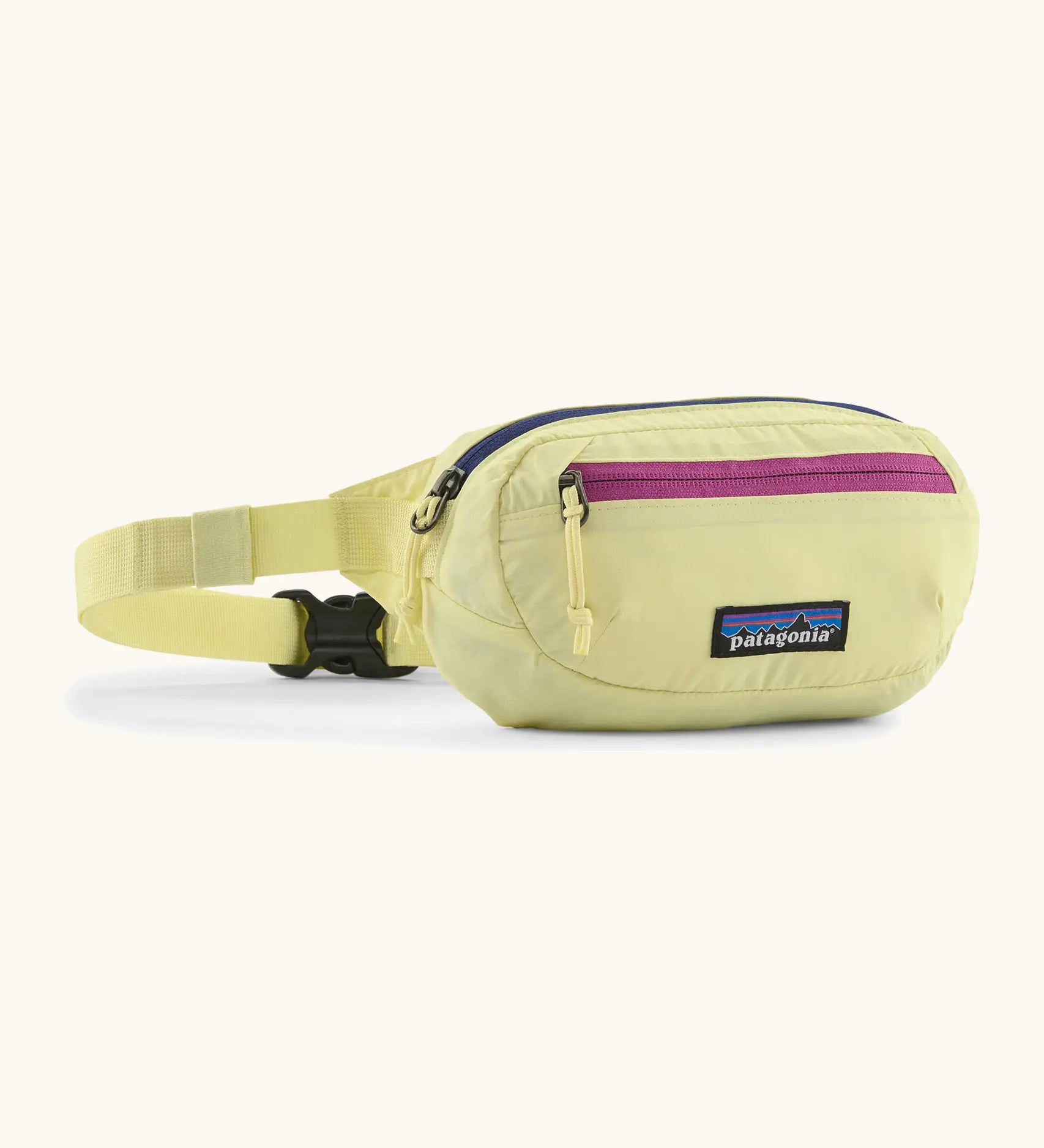 Patagonia 100% recycled nylon weather resistant terravia mini hip pack in pale yellow. Features 2 compartments with navy and pink zip detail