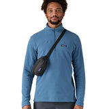 Man wearing Patagonia's terravia mini hip pack in black over the shoulder shows the front zipped pocket