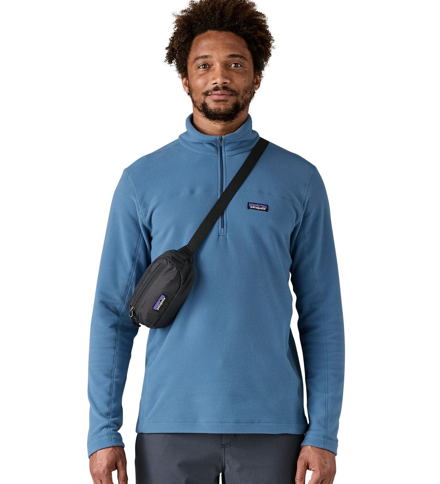 Man wearing Patagonia's terravia mini hip pack in black over the shoulder shows the front zipped pocket