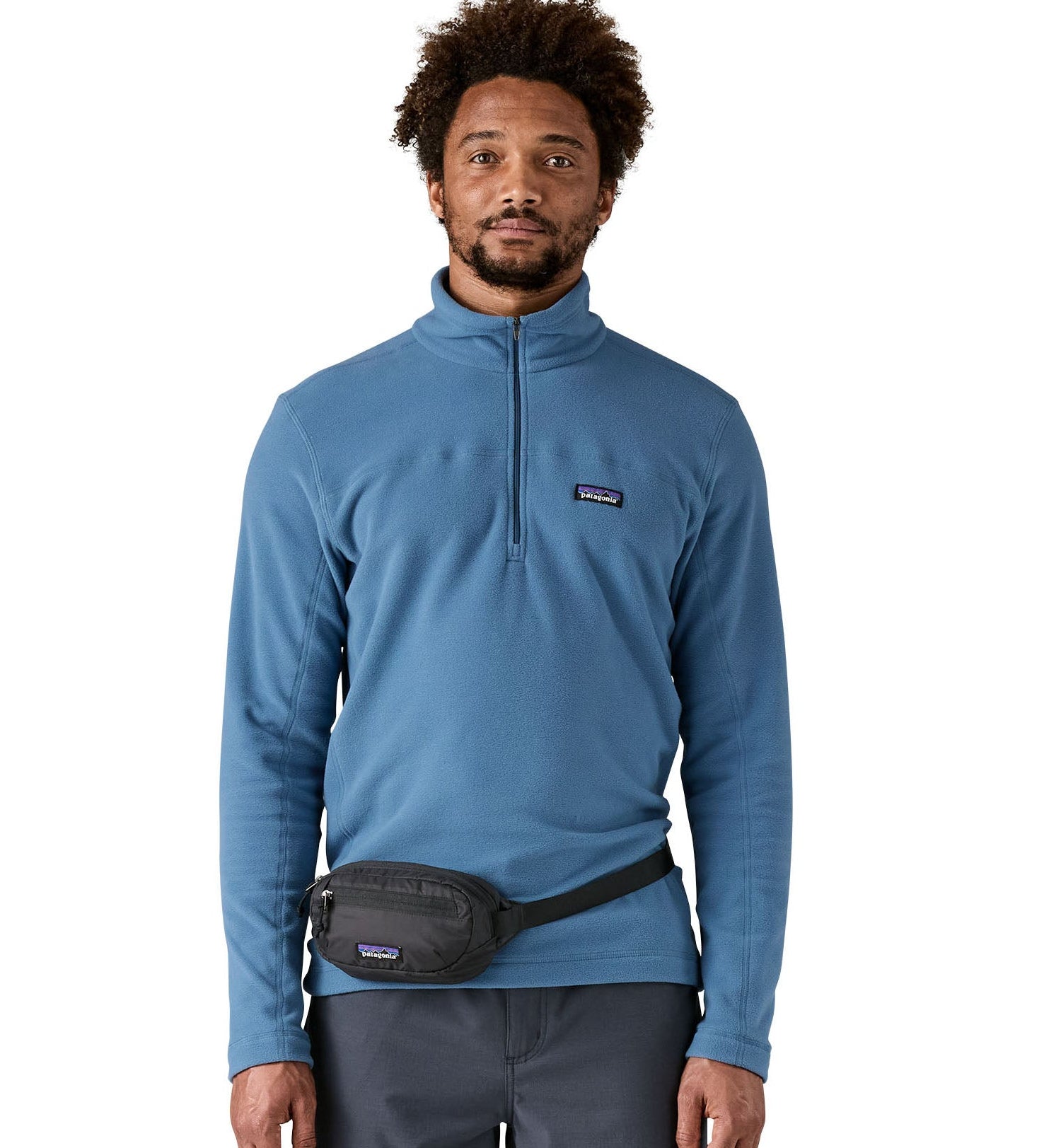 Man wearing Patagonia's terravia mini hip pack in black around the waist shows the front zipped pocket