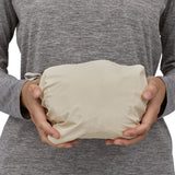 A person holding the Patagonia Women's Torrentshell 3L Rain Jacket whilst its in its storage bag. The coat is able to fit in two hands and is compact when stored in the bag