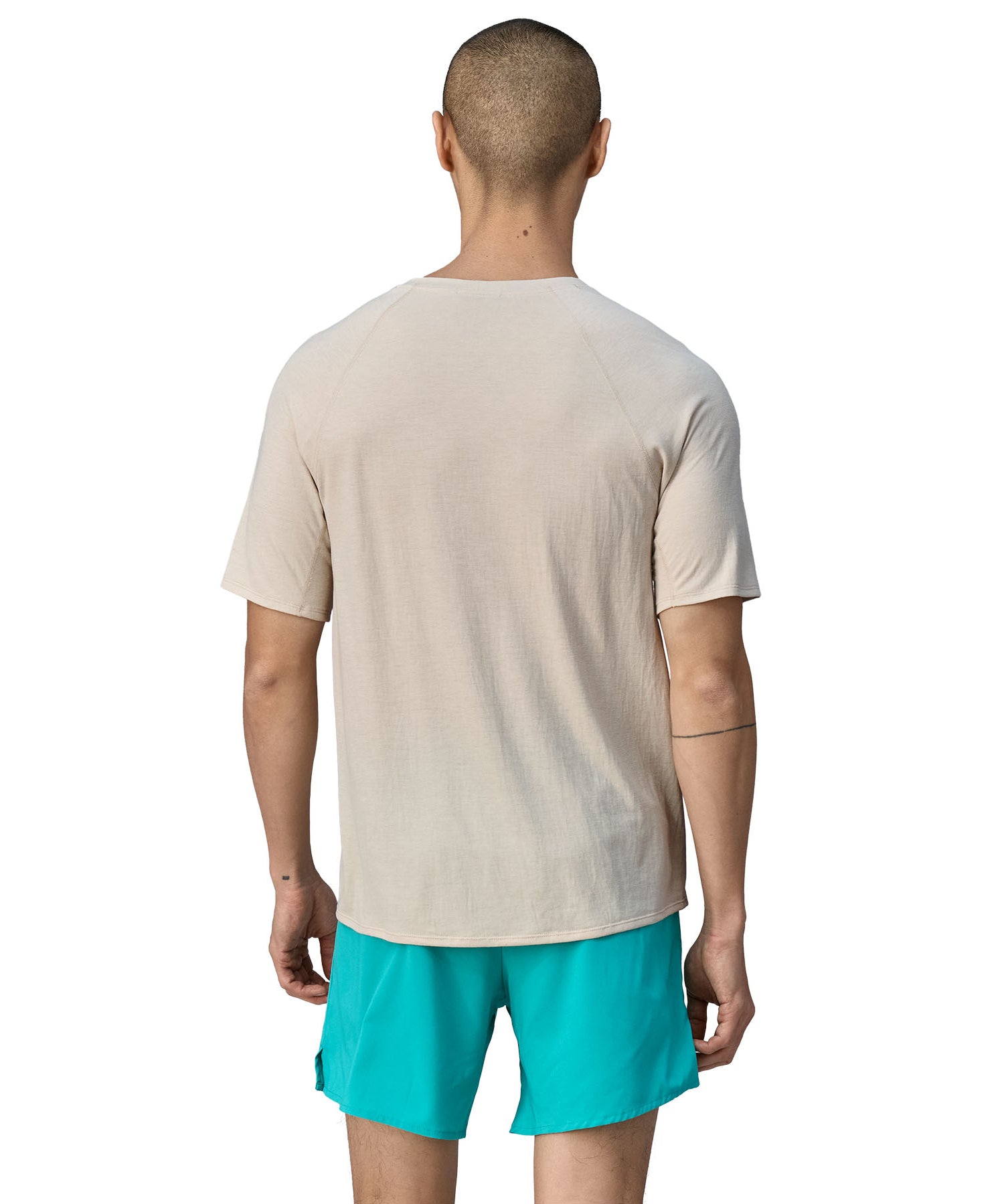A person wearing light blue shorts, is wearing the Patagonia Men's Cap Cool Trail Graphic T-Shirt to show the fit from the black