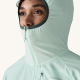 A close up of a female wearing the Patagonia lightweight jacket in light turquoise with the hood up and zip fully fastened 