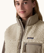 A close up of the Patagonia thick cream fleece showing the dark cream turned up collar, zip detail and cream patch pocket