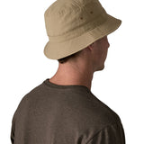 The back of man wearing Patagonia's 100% recycled nylon water repellent adult bucket hat in light brown. Shows 2 air holes on the side