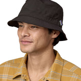 Man wearing Patagonia's 100% recycled nylon water repellent adult bucket hat in black. Shows 2 air holes on the side