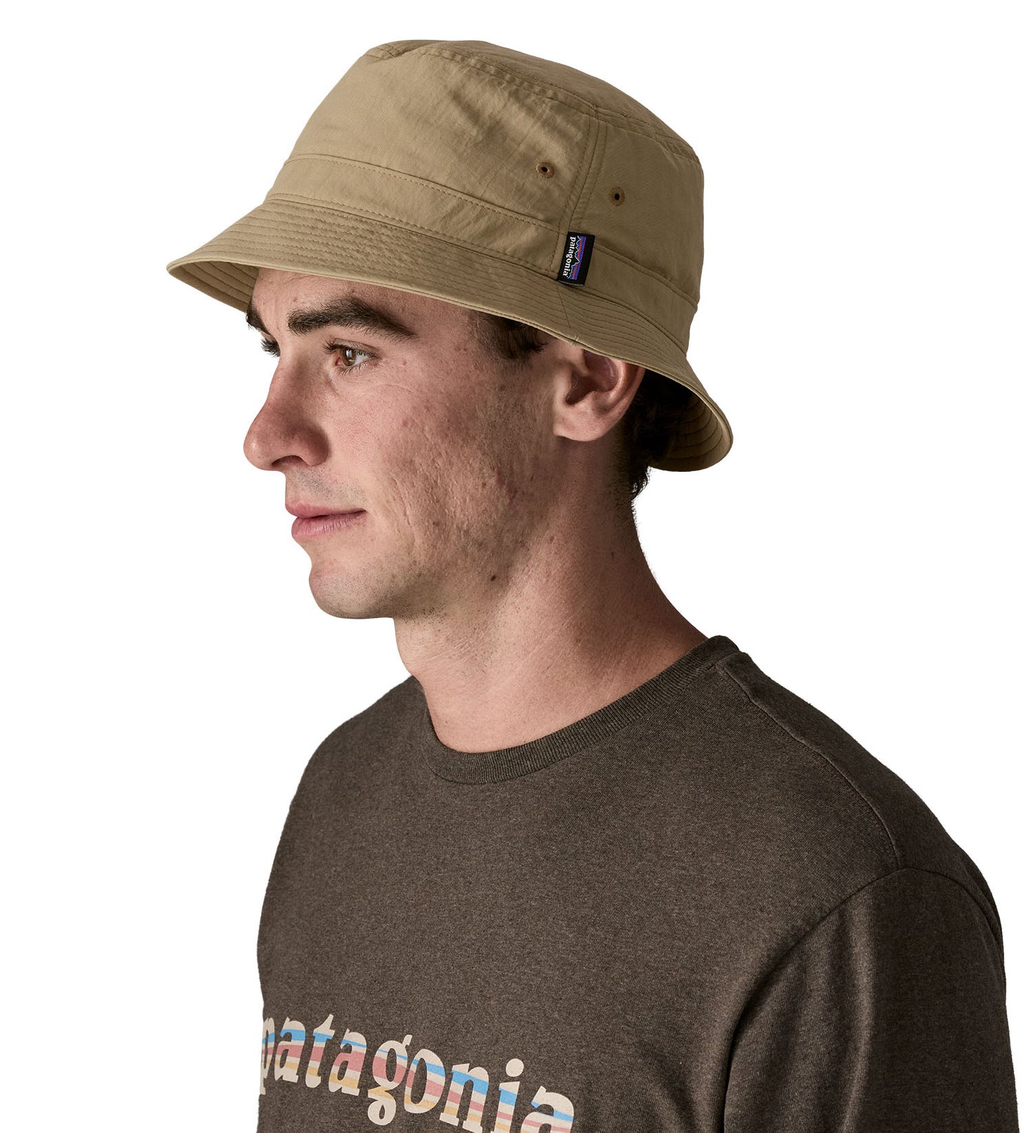 Man wearing Patagonia's 100% recycled nylon water repellent adult bucket hat in light brown. Shows 2 air holes on the side