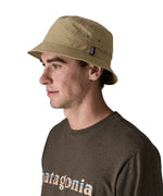 Side of man wearing Patagonia's breathable quick drying wavefarer bucket hat in khaki green 