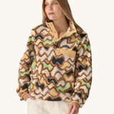 Woman wearing the Patagonia Women’s Lightweight Synchilla Snap-T Fleece in the Small Currents print, featuring pastel purple, green, and brown waves on a beige background, with a front breast pocket and collar poppers. For sale at Babipur.