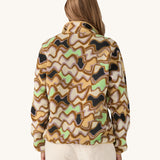 Patagonia Women’s Lightweight Synchilla Snap-T Fleece in Small Currents shown on a woman; beige fleece with pastel wave pattern in purple, green, and brown, plus a breast pocket and snap-button collar. Available at Babipur.