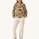 Woman modelling the Patagonia Lightweight Synchilla Snap-T Fleece, Small Currents design—beige with soft purple, green, and brown waves, front pocket, and snap collar. Sold at Babipur.