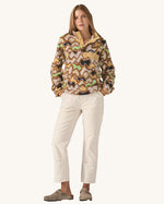 Woman modelling the Patagonia Lightweight Synchilla Snap-T Fleece, Small Currents design—beige with soft purple, green, and brown waves, front pocket, and snap collar. Sold at Babipur.