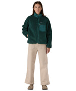 A woman wearing the Patagonia classic retro x women's jacket in cascade green available at Babipur. 