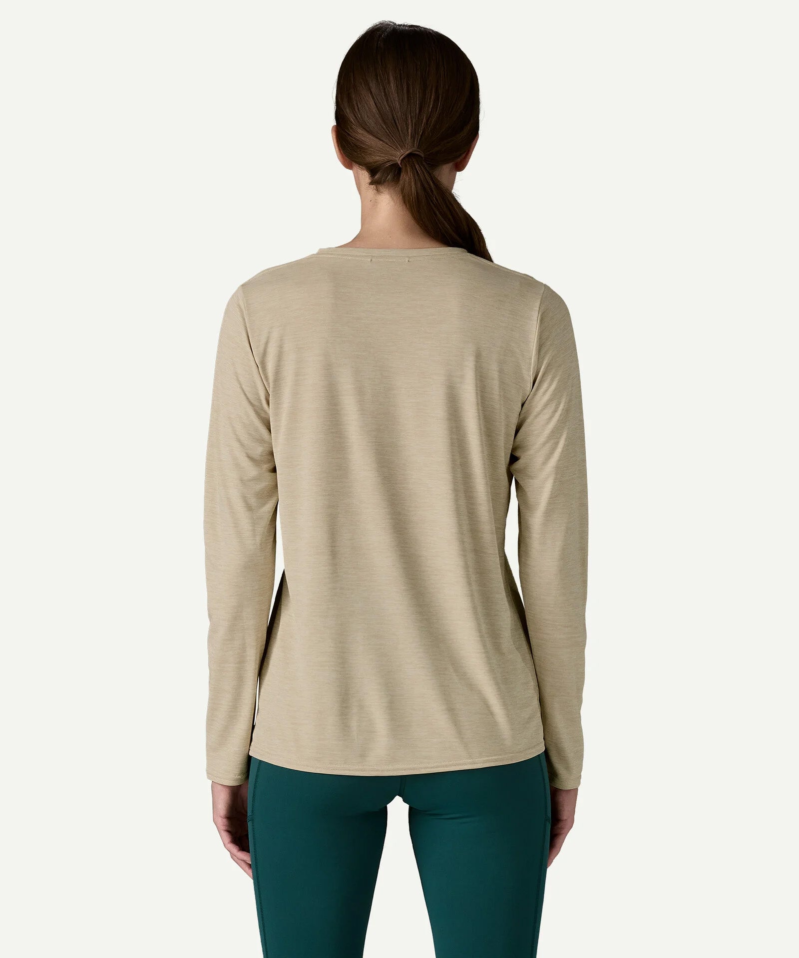 Back view of a woman wearing the Patagonia Women’s Long Sleeved Capilene Cool Daily Graphic Shirt in Fitz Roy Foliage, showcasing the long sleeved technical fabric.