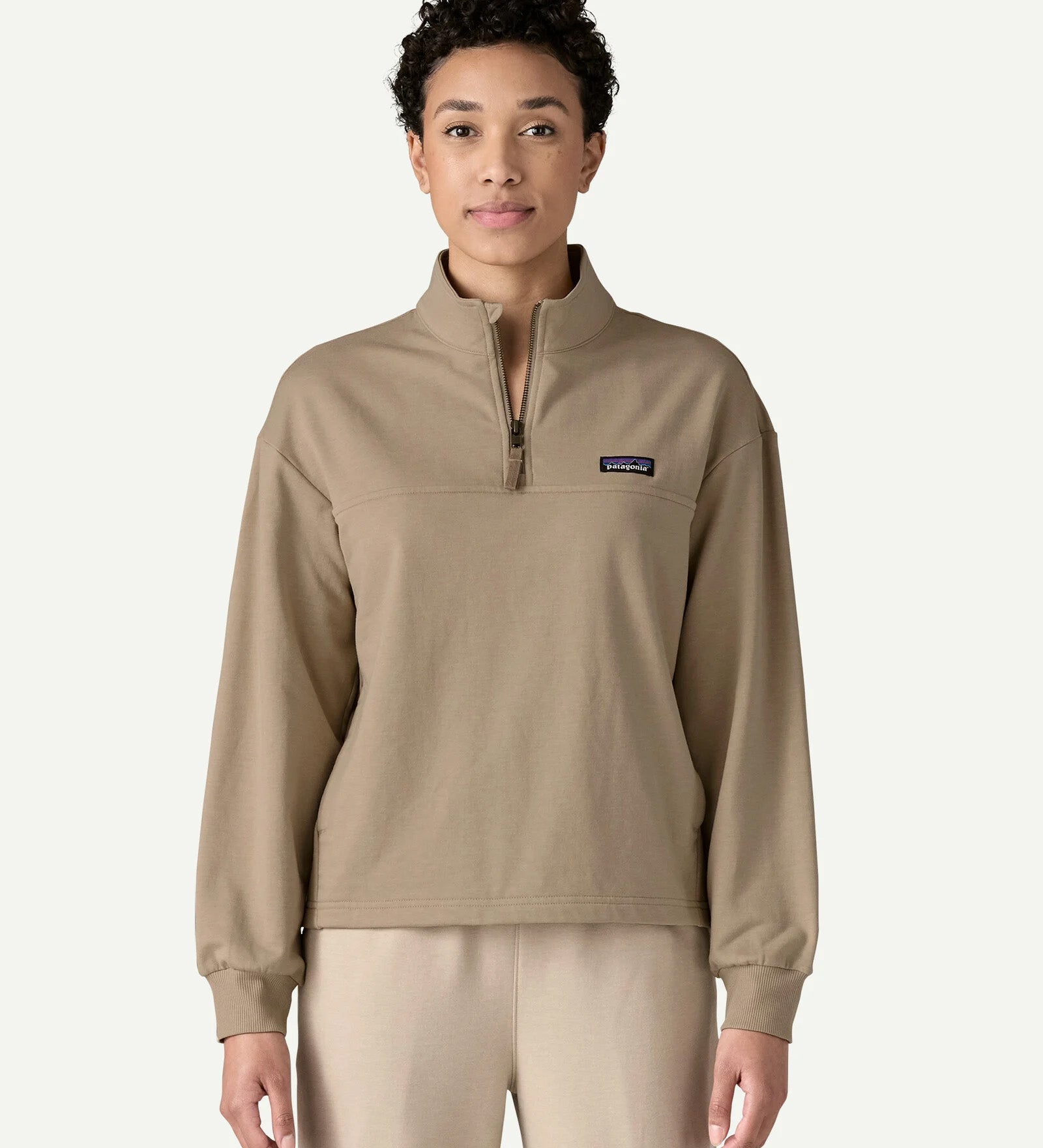 Front view of a woman wearing the Patagonia Women’s Ahnya Pullover in Seabird Grey, featuring the 1/4 zip collar, kangaroo handwarmer pockets and small Patagonia logo on the left chest.