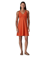 Woman wearing Patagonia's amber dawn sleeveless dress in orange.  Dress  has front low v neck and knee-height