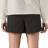 Back of woman wearing Patagonia's quick drying women's baggies shorts in black. Shorts have a loose fit