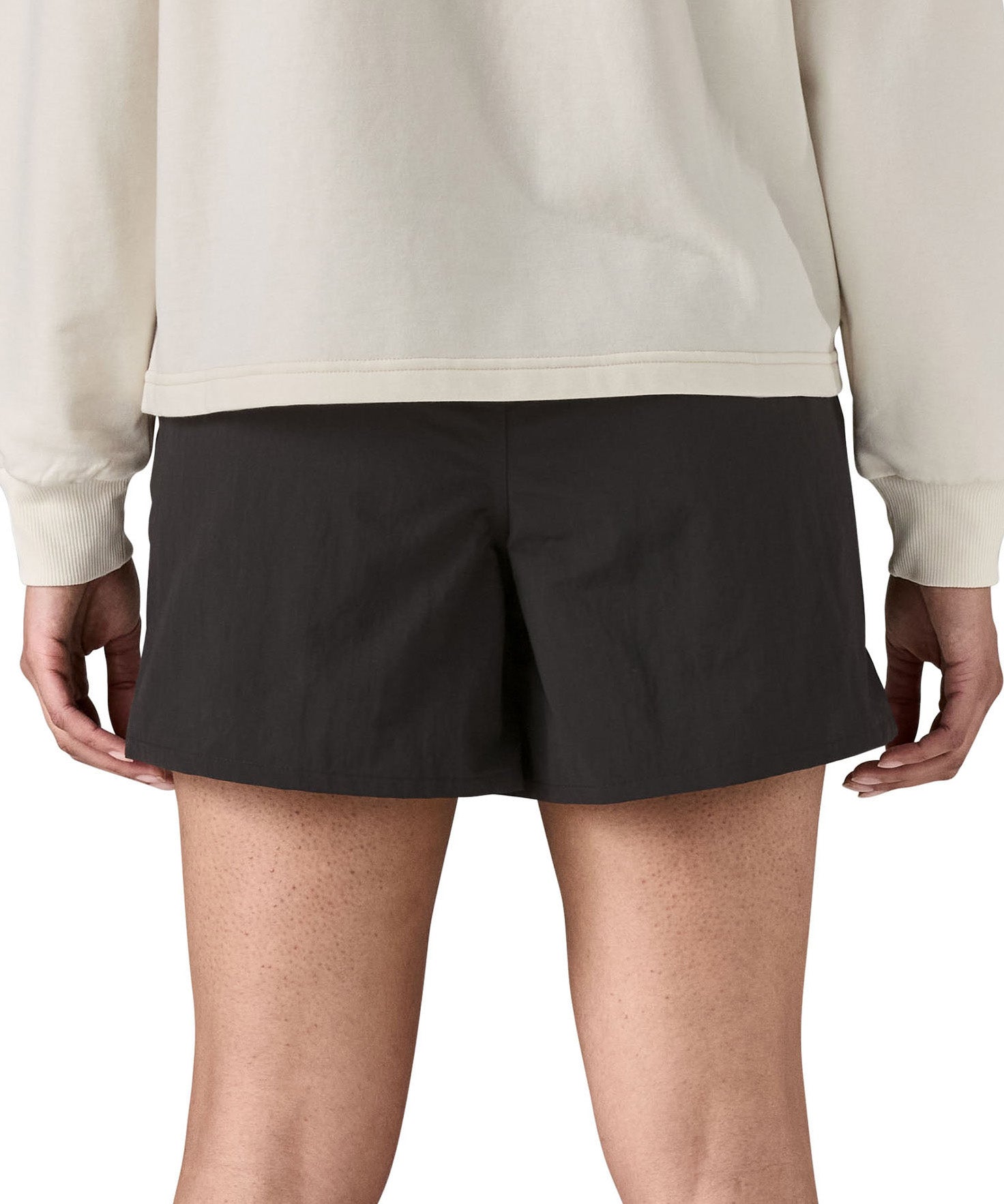 Back of woman wearing Patagonia's quick drying women's baggies shorts in black. Shorts have a loose fit