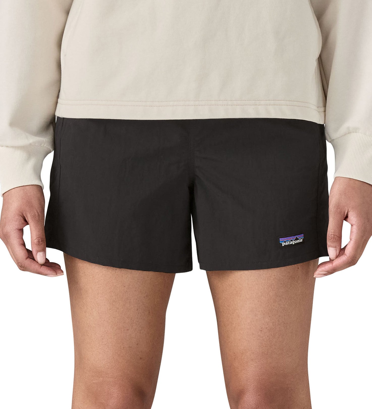 Woman wearing Patagonia quick drying women's baggies shorts in black. Shorts have a loose fit