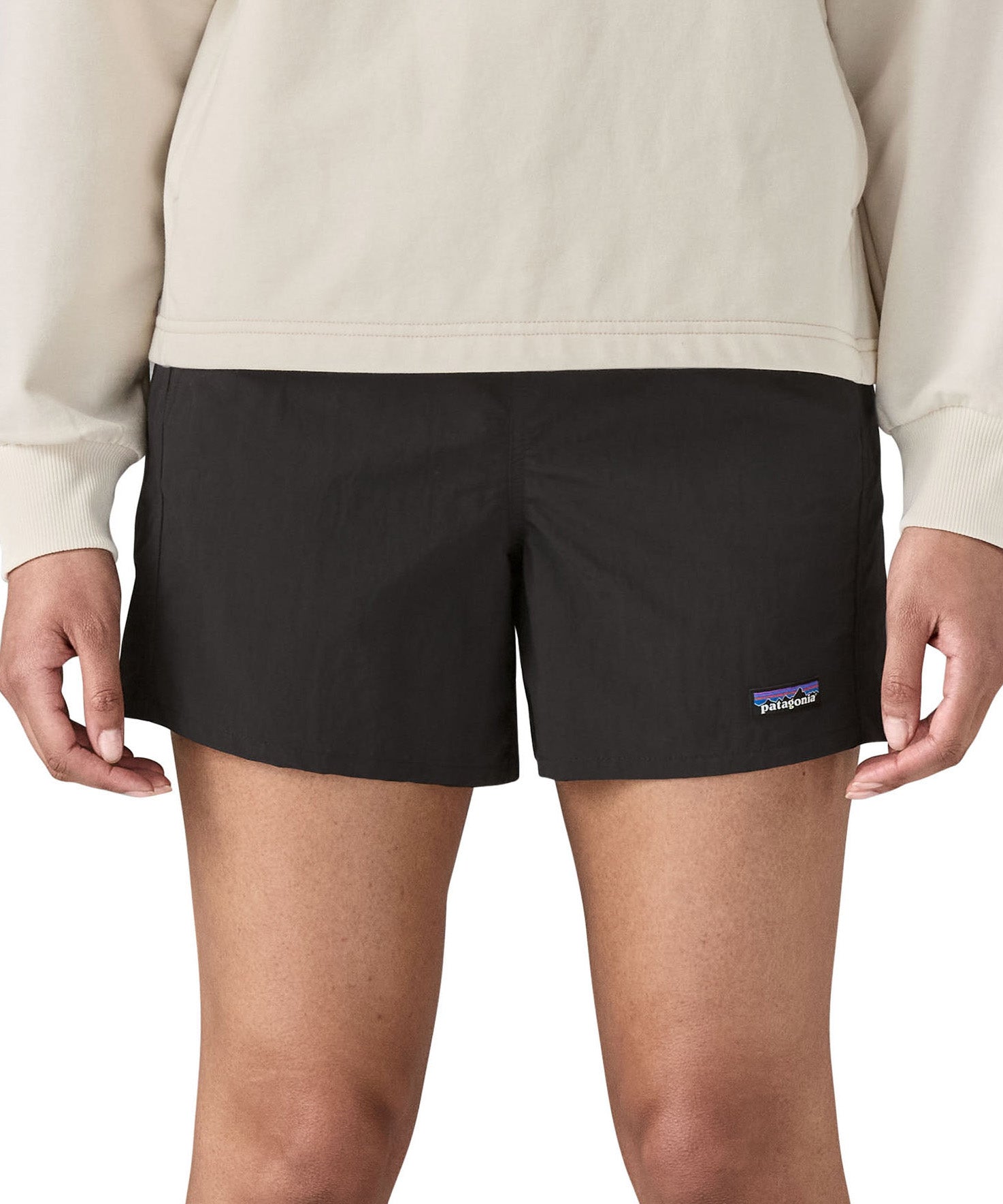 Woman wearing Patagonia quick drying women's baggies shorts in black. Shorts have a loose fit