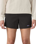 Woman wearing Patagonia quick drying women's baggies shorts in black. Shorts have a loose fit