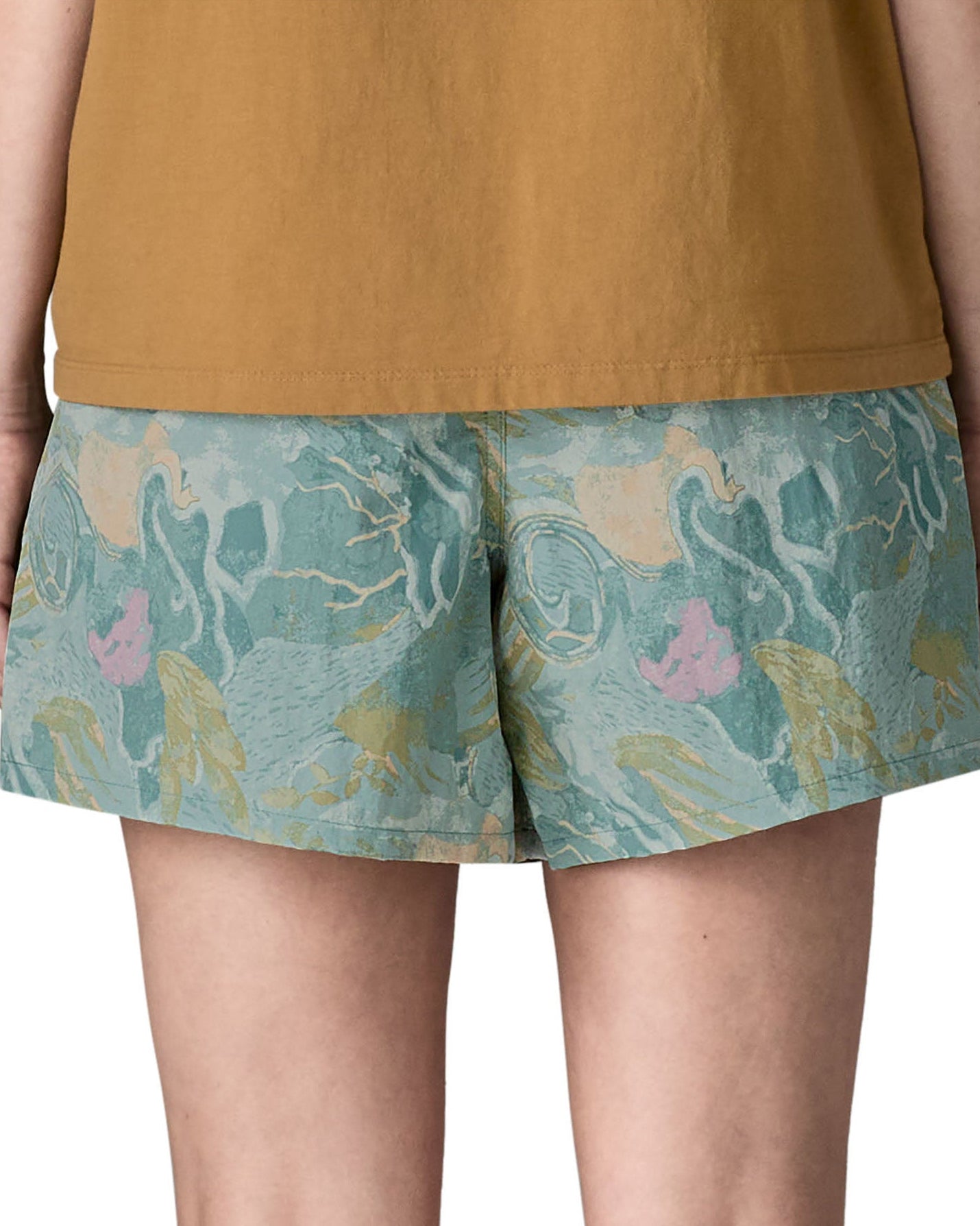Back of Side of woman wearing Patagonia's women's baggies shorts in black with repeating abstract design. Shorts have a loose fit