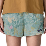Woman wearing Patagonia quick drying women's baggies shorts in light blue with repeating abstract design. Shorts have a loose fit