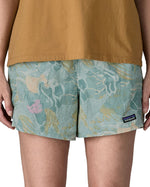 Woman wearing Patagonia quick drying women's baggies shorts in light blue with repeating abstract design. Shorts have a loose fit