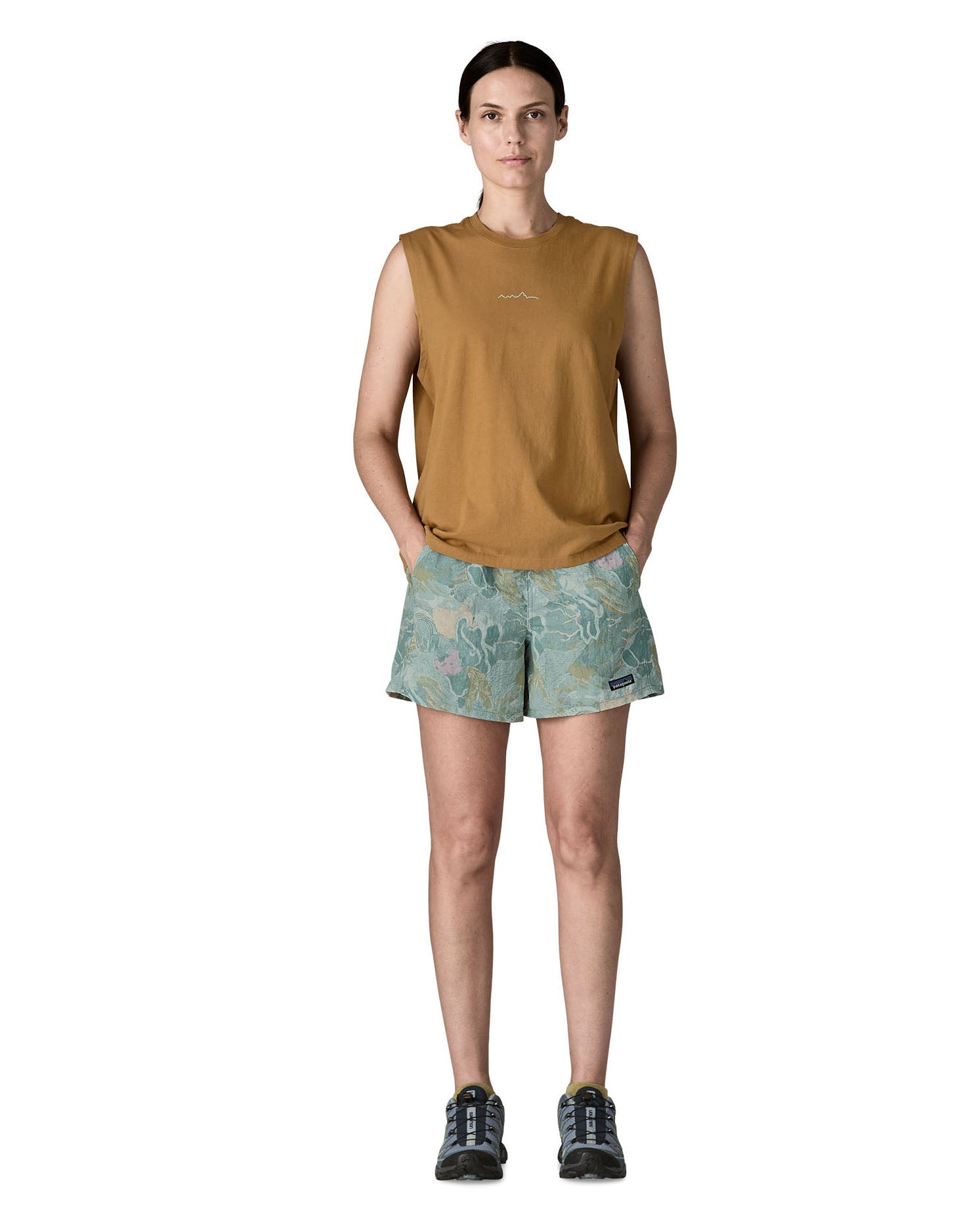 Woman wearing Patagonia quick drying women's baggies shorts in light blue with repeating abstract design with hands in side pockets