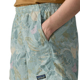 Side of woman wearing Patagonia quick drying women's baggies shorts in light blue with repeating abstract design with hand in pocket