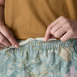 Close up of woman wearing Patagonia's light blue baggies shorts with repeating abstract design pulling on waist cord