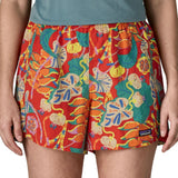 Woman wearing Patagonia quick drying women's baggies shorts in red with repeating abstract tropical design. Shorts have a loose fit