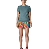 Woman wearing Patagonia quick drying women's baggies shorts in red with repeating abstract design. Shorts have loose fit