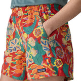 Woman wearing Patagonia quick drying women's baggies shorts in red with abstract design with hand in side pocket