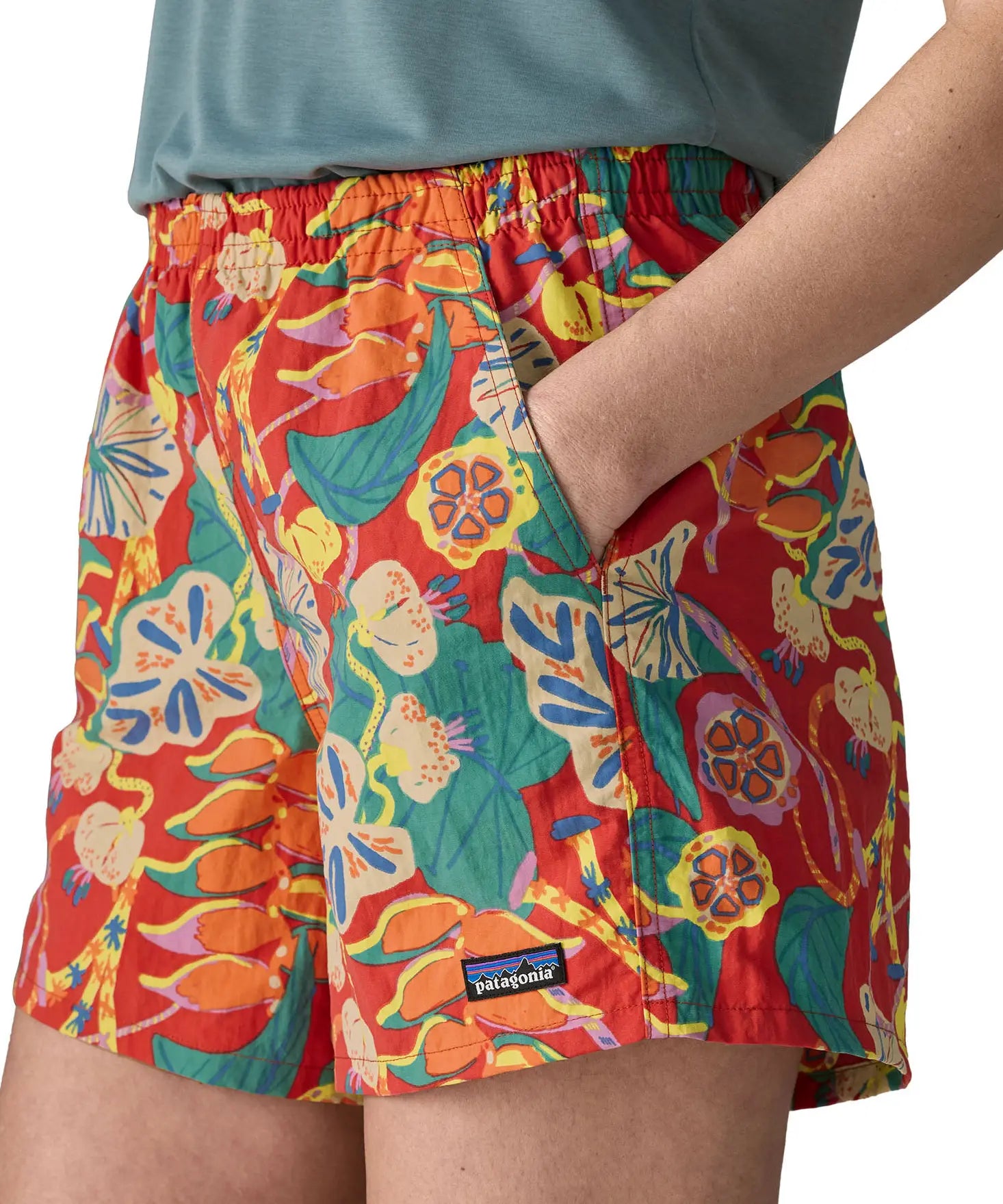 Woman wearing Patagonia quick drying women's baggies shorts in red with abstract design with hand in side pocket