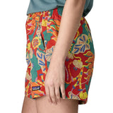 Side of woman wearing Patagonia quick drying women's baggies shorts in red with repeating abstract tropical design 